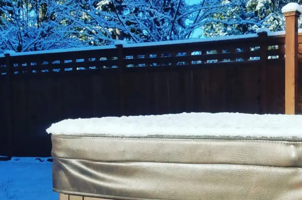 A mattress with snow on it in front of trees.